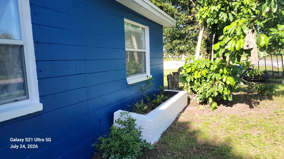 Blue lap siding with white window trim and painted block planter, exterior painting in Brevard County, FL