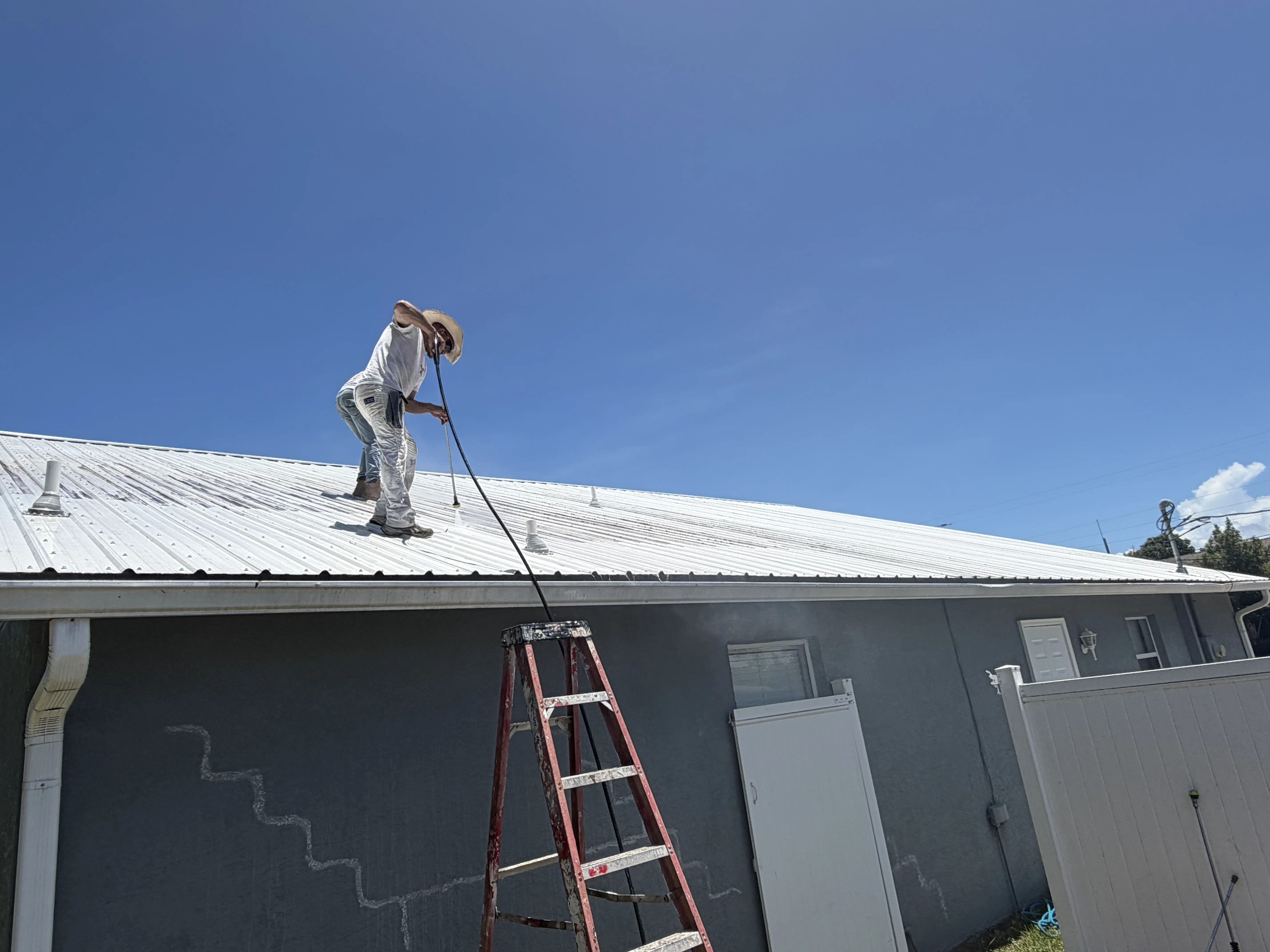 Pressure cleaning a metal roof prior to painting in Brevard County, FL by Paint Craft of Brevard